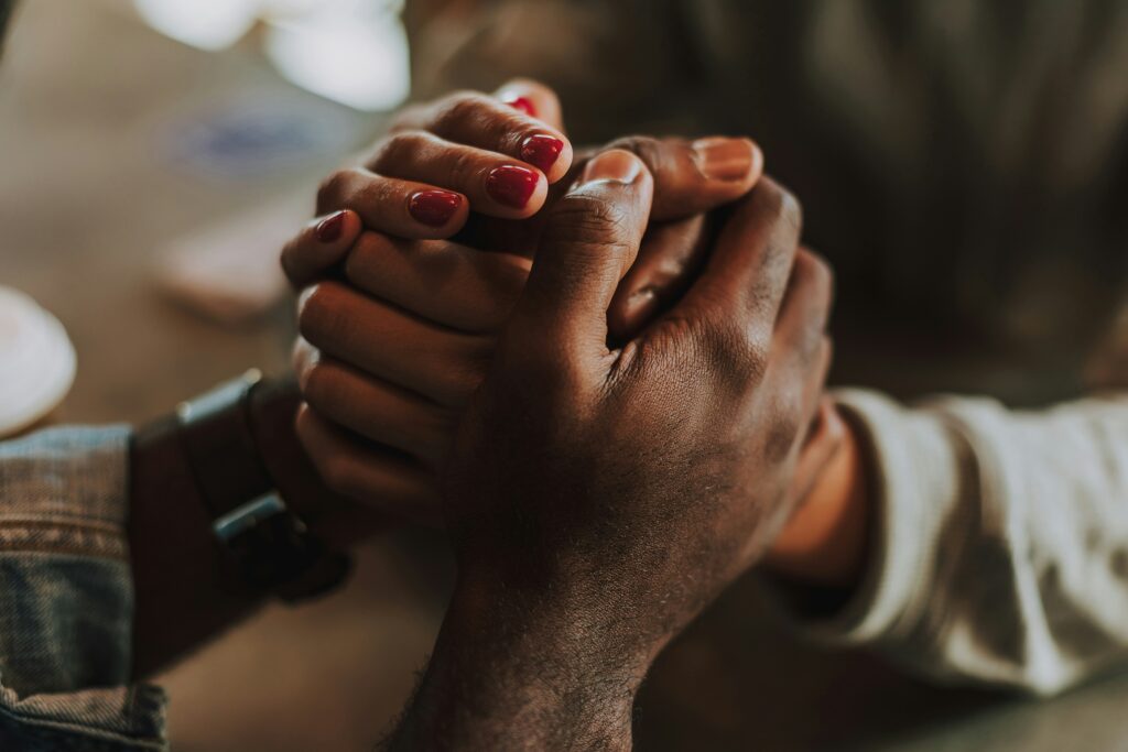 Close-up of two people holding hands, conveying a sense of support and connection.